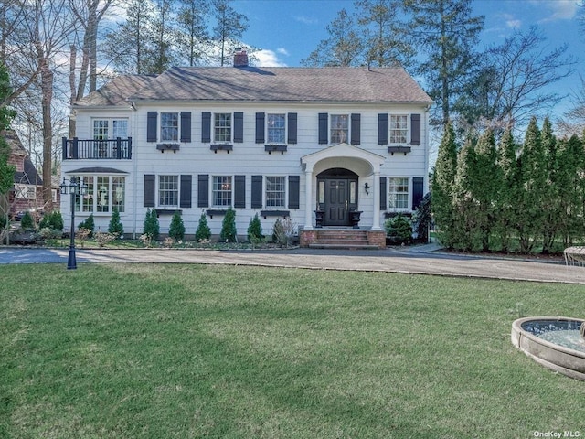 colonial home with a chimney and a front lawn