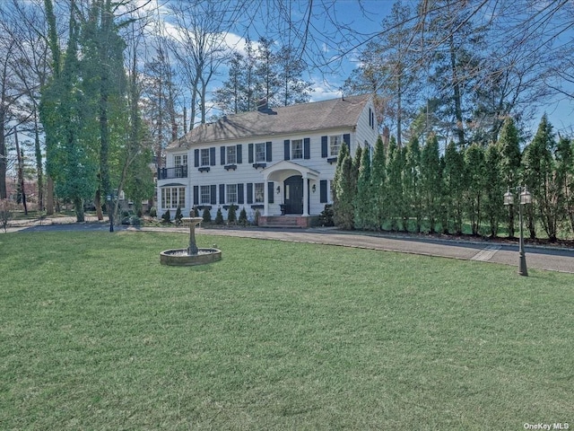 colonial home featuring a chimney and a front lawn