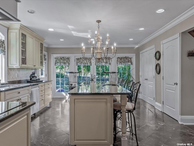 kitchen with dishwasher, a kitchen island, a breakfast bar area, ornamental molding, and cream cabinetry