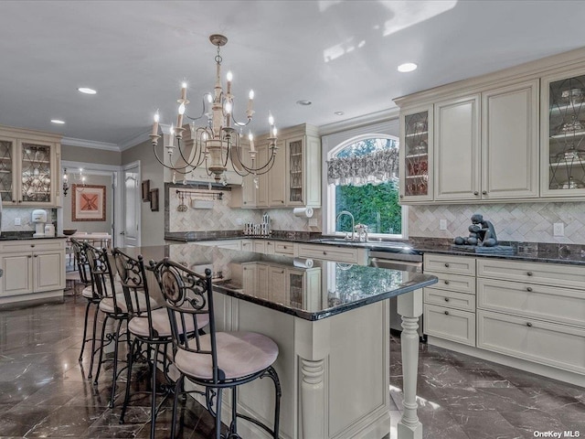 kitchen featuring marble finish floor, cream cabinets, ornamental molding, and dishwasher