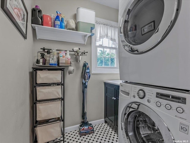 laundry area with cabinet space, baseboards, and stacked washer / drying machine