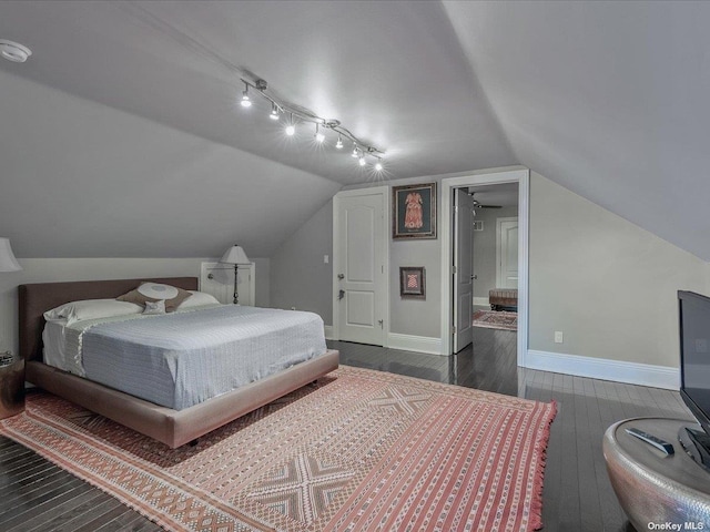 bedroom featuring lofted ceiling, connected bathroom, hardwood / wood-style flooring, and baseboards