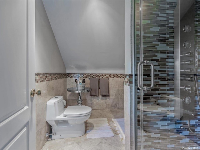 bathroom with vaulted ceiling, a shower stall, toilet, and tile walls