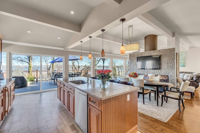 kitchen with a sink, open floor plan, stainless steel dishwasher, light stone countertops, and pendant lighting