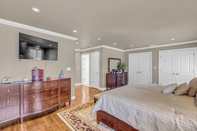 bedroom featuring baseboards, recessed lighting, light wood-style flooring, and multiple closets