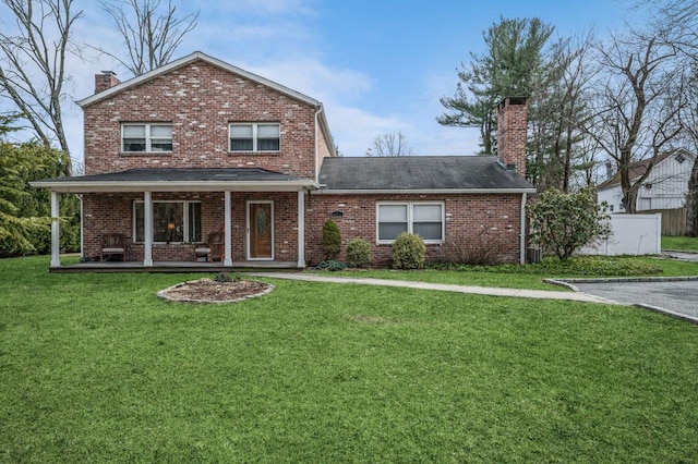 traditional home with a front lawn, covered porch, brick siding, and a chimney