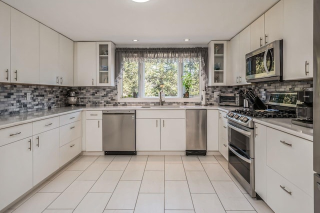 kitchen with backsplash, appliances with stainless steel finishes, light countertops, and a sink