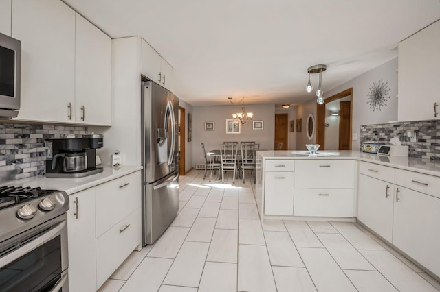 kitchen featuring decorative light fixtures, light countertops, appliances with stainless steel finishes, a peninsula, and white cabinets