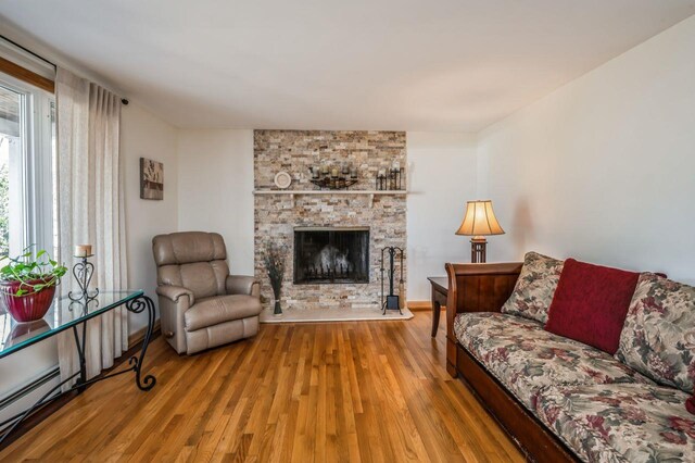 living room with a stone fireplace, wood finished floors, and baseboards