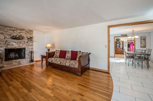 living room featuring baseboards, an inviting chandelier, wood finished floors, and a fireplace