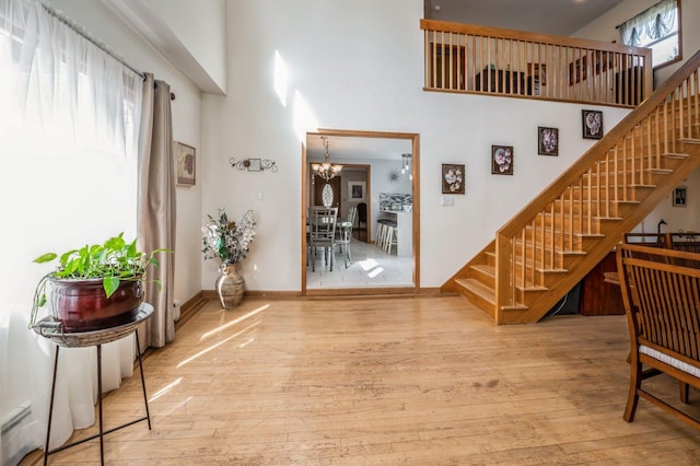 foyer entrance with stairway, an inviting chandelier, a towering ceiling, and hardwood / wood-style floors