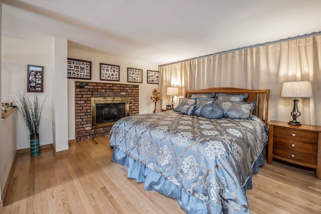 bedroom featuring a fireplace, wood finished floors, and baseboards