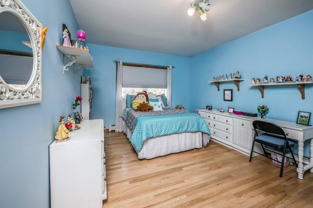 bedroom with baseboard heating and light wood finished floors