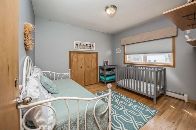 bedroom with a baseboard heating unit and wood finished floors