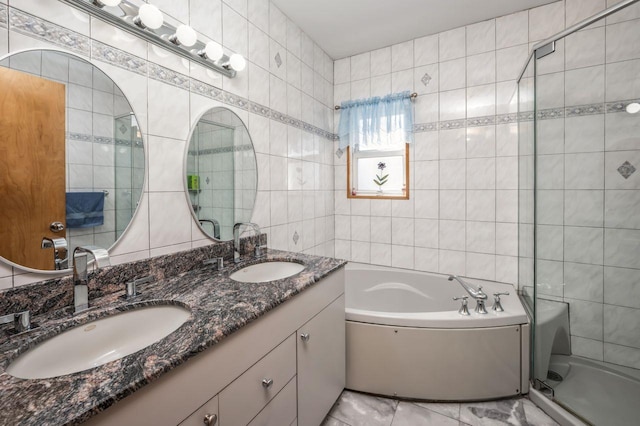 full bathroom with double vanity, tile walls, a garden tub, and a sink