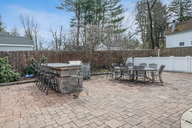 view of patio with outdoor dry bar, outdoor dining area, and a fenced backyard