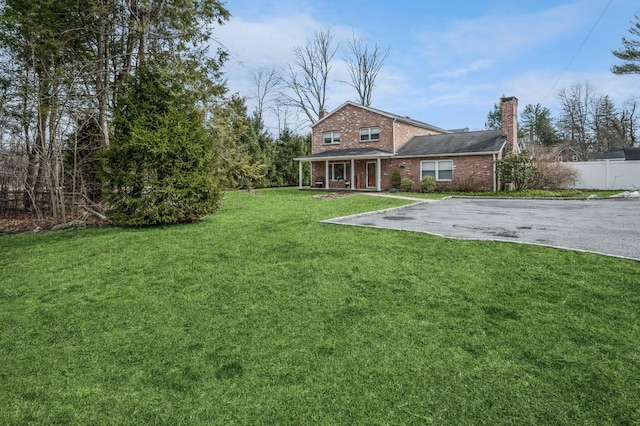 view of yard with aphalt driveway and fence