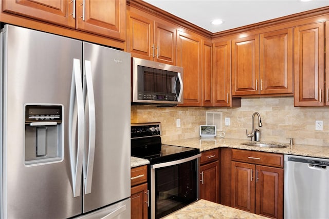 kitchen featuring stainless steel appliances, tasteful backsplash, a sink, and brown cabinets