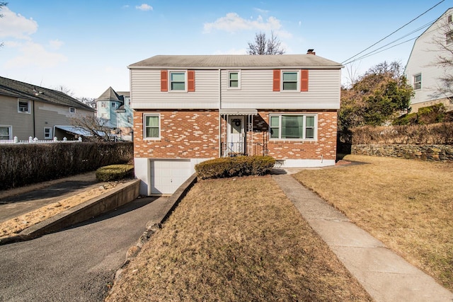 colonial home with aphalt driveway, a garage, brick siding, fence, and a front yard