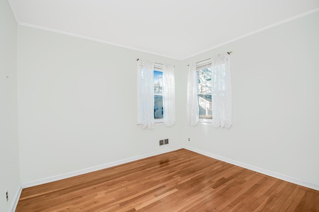 unfurnished room with ornamental molding, light wood finished floors, visible vents, and baseboards