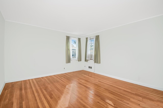 empty room with baseboards, crown molding, and light wood finished floors