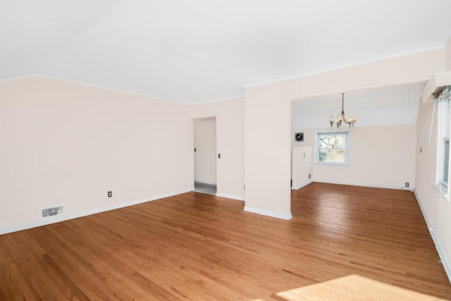 spare room with a notable chandelier, visible vents, baseboards, light wood-style floors, and ornamental molding