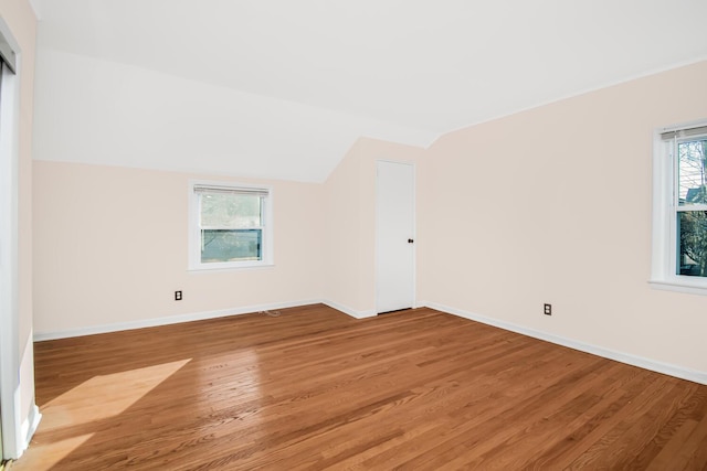 unfurnished room with vaulted ceiling, light wood-style flooring, and baseboards