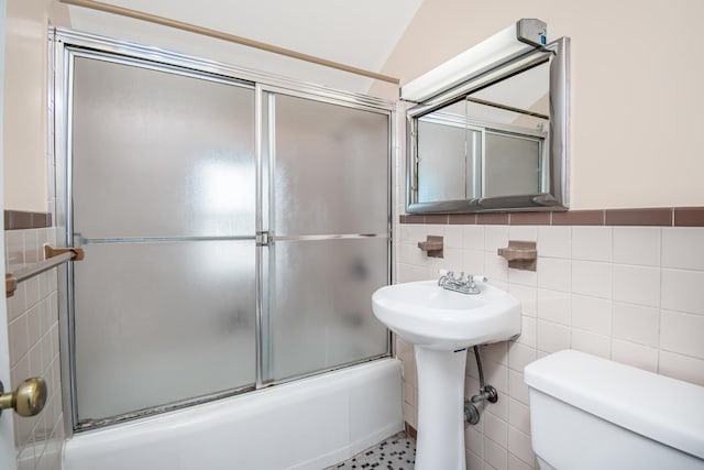 bathroom featuring toilet, vaulted ceiling, tile walls, and enclosed tub / shower combo