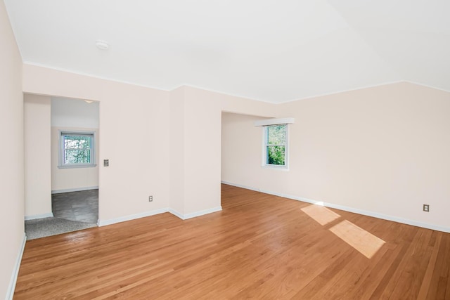 unfurnished room featuring light wood-style flooring, baseboards, and a wealth of natural light