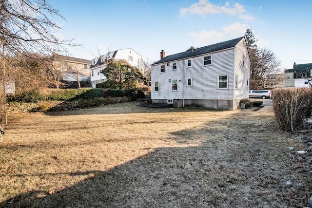 rear view of property with a lawn and a chimney