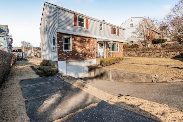 colonial home featuring driveway, brick siding, an attached garage, and fence