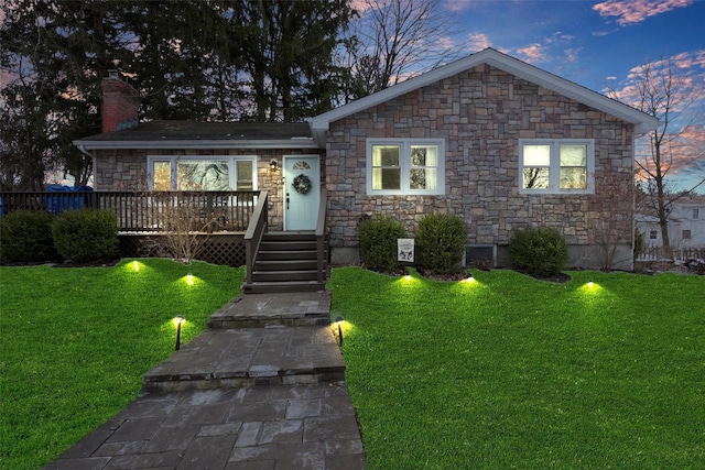 view of front of property featuring a yard, a chimney, and a wooden deck