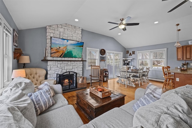 living area with a ceiling fan, vaulted ceiling, and light wood-style flooring