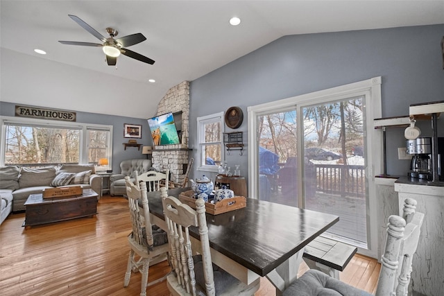 dining space with vaulted ceiling, a stone fireplace, wood finished floors, and recessed lighting