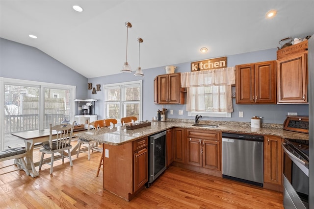 kitchen featuring brown cabinets, a breakfast bar area, appliances with stainless steel finishes, beverage cooler, and a peninsula