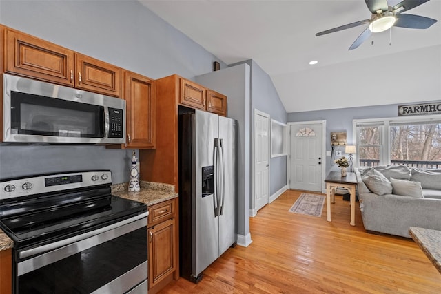 kitchen featuring lofted ceiling, light wood-style flooring, stainless steel appliances, open floor plan, and brown cabinets