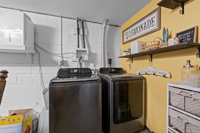 washroom with laundry area, washer and clothes dryer, and concrete block wall