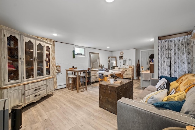 living area featuring concrete block wall, a baseboard radiator, light wood-style flooring, and recessed lighting