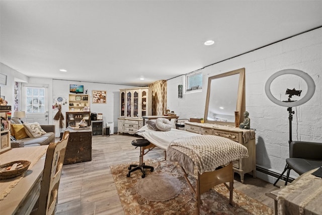 bedroom featuring concrete block wall, light wood-style flooring, a baseboard heating unit, and recessed lighting