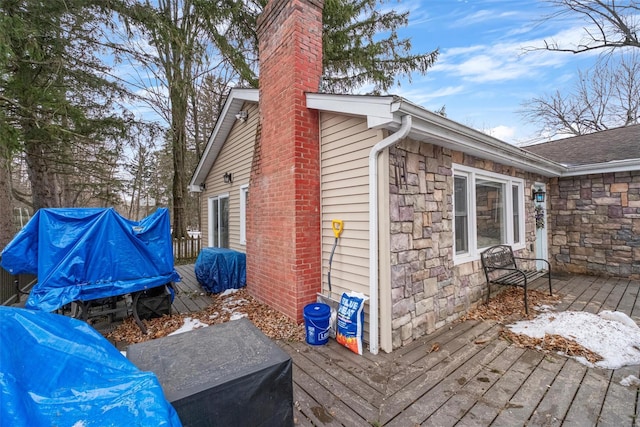 view of property exterior with stone siding, a chimney, and a wooden deck