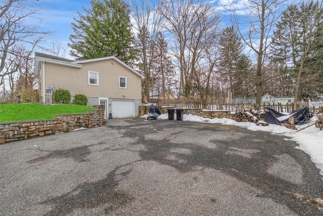 view of side of home featuring an attached garage and aphalt driveway