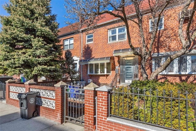 view of property with a fenced front yard, a gate, and brick siding