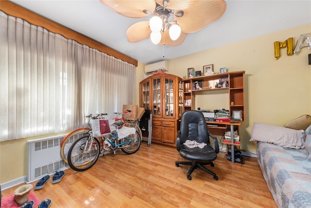 home office with a ceiling fan, radiator, a wall unit AC, and light wood finished floors