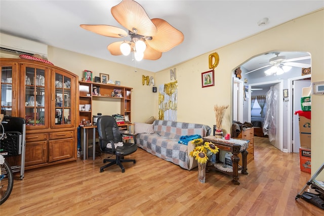 office with a wall unit AC, light wood-style floors, ceiling fan, and arched walkways