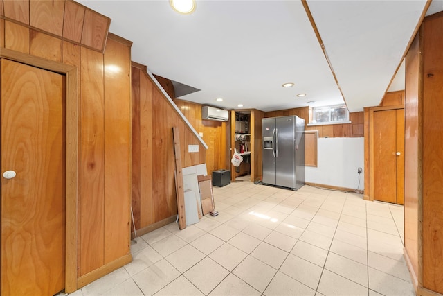 basement with recessed lighting, light tile patterned flooring, wood walls, stainless steel fridge, and a wall mounted air conditioner