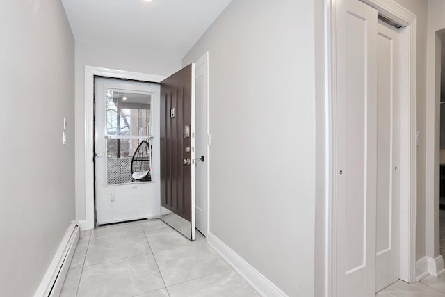 hallway with light tile patterned floors, baseboard heating, and baseboards