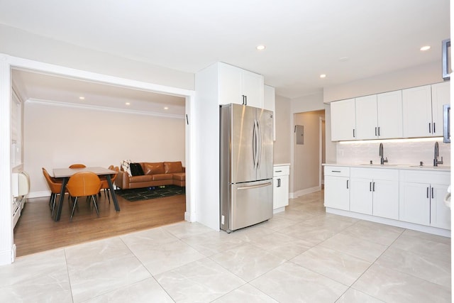 kitchen featuring a baseboard radiator, backsplash, freestanding refrigerator, light countertops, and a sink