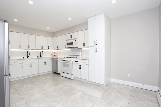 kitchen with white cabinetry, appliances with stainless steel finishes, light countertops, and backsplash