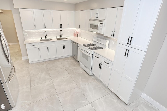 kitchen with light countertops, decorative backsplash, appliances with stainless steel finishes, white cabinets, and a sink