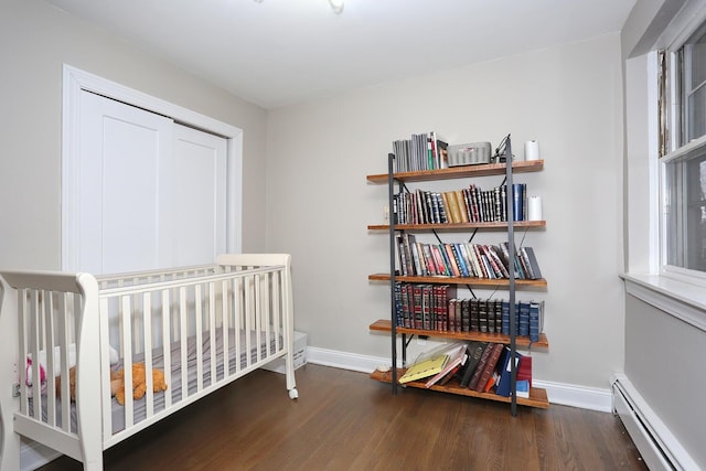 bedroom with a baseboard radiator, baseboards, and wood finished floors